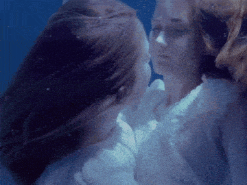 a woman in a white dress is kissing another woman in the water