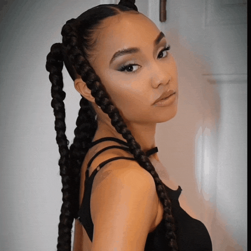 a woman with braids in her hair wearing a black tank top