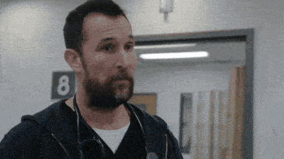 a man with a beard and a stethoscope around his neck is standing in a hallway with the number 8 on the wall
