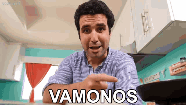 a man in a kitchen is pointing at a pan and says vamonos