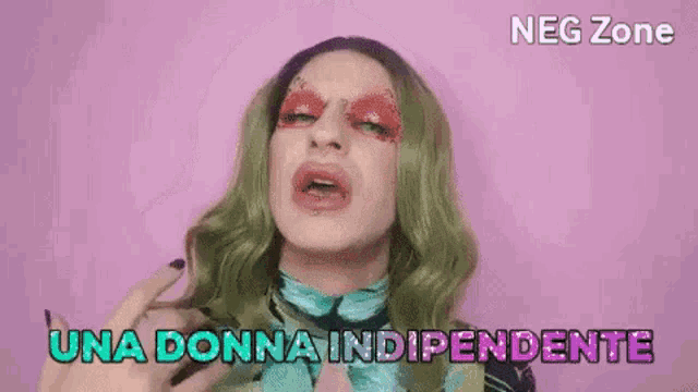 a woman with green hair and red eye shadow is making a funny face and says una donna independente .