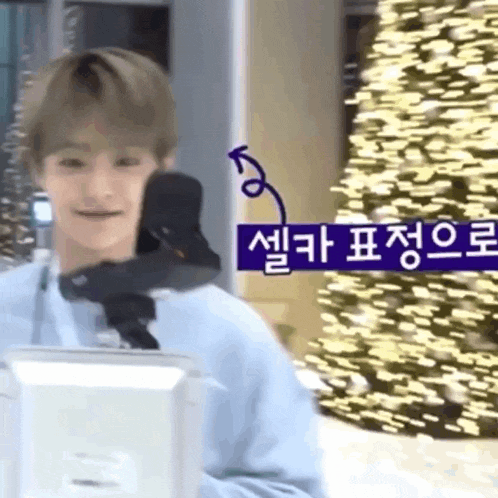 a man is standing in front of a christmas tree and talking into a microphone .