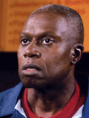 a close up of a man 's face with a blue jacket and a red shirt