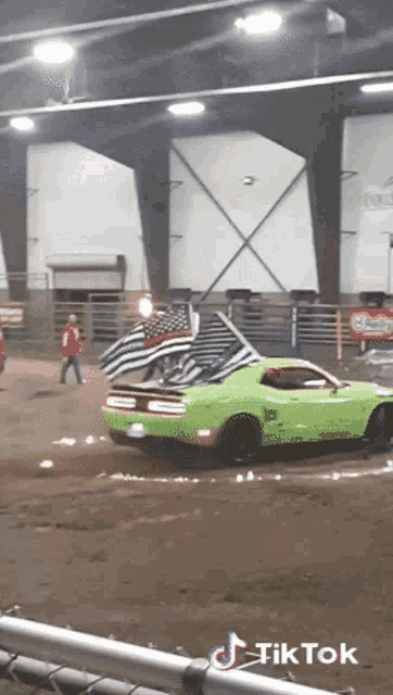a green dodge challenger is driving down a dirt track