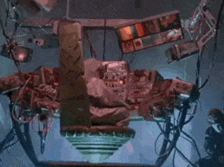a statue of a man is sitting in a machine with lots of wires .