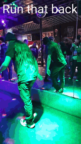 a man in a green shirt is dancing in front of a mirror with the words run that back below him