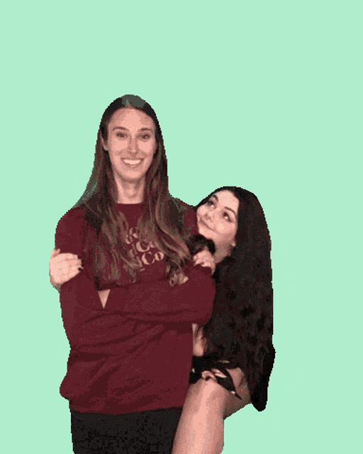 two women are posing for a picture with one wearing a maroon sweatshirt that says ' iowa ' on it