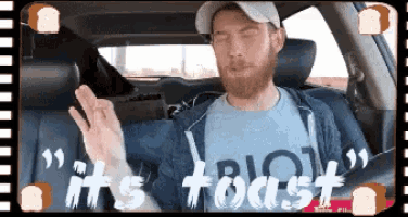 a man wearing a shirt that says it 's toast is sitting in a car