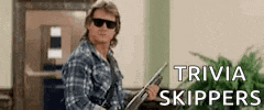 a man wearing sunglasses and a plaid shirt is holding a gun in front of a sign that says trivia skippers .