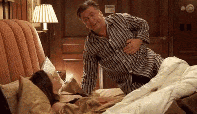 a man is standing next to a woman laying in bed .