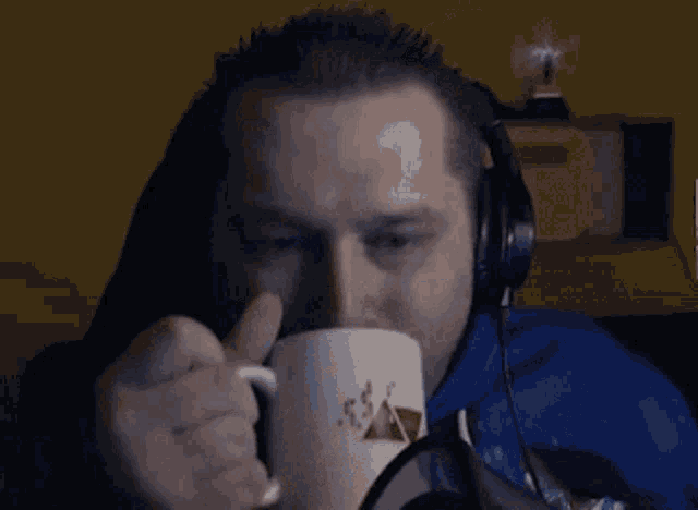 a man wearing headphones is holding a mug with a picture of a pyramid on it