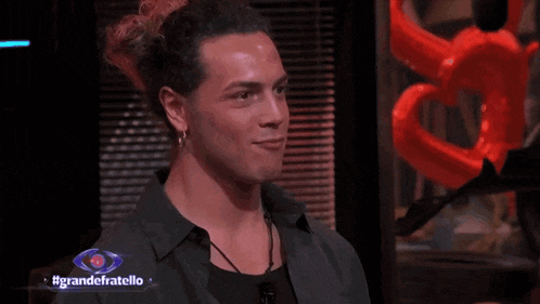 a man is smiling in front of a sign that says grande fratello