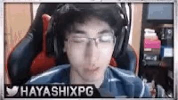 a young man wearing headphones and glasses is sitting in a gaming chair .