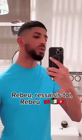 a man in a blue shirt is taking a picture of himself in the mirror
