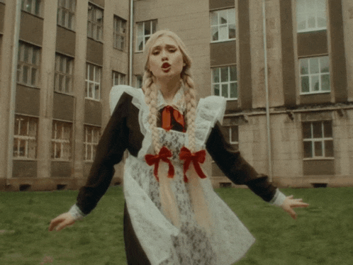 a girl in a school uniform is standing in front of a building with her arms outstretched
