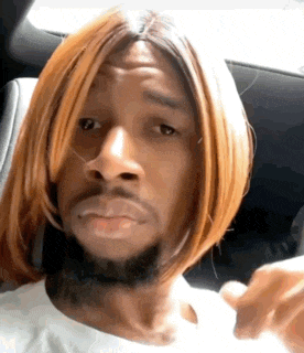 a man wearing a wig and a beard is making a funny face in a car .