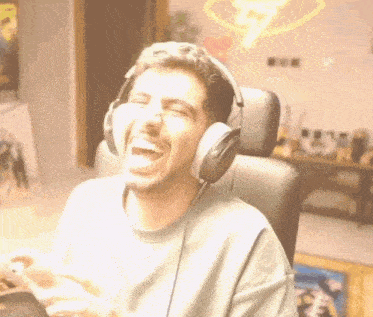 a man wearing headphones is sitting in a chair and laughing