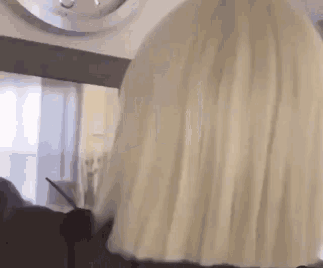 a woman with blonde hair is standing in a room with a clock on the wall .