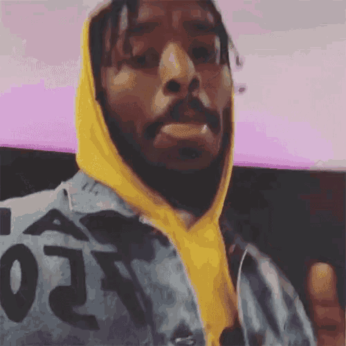 a man wearing a yellow hoodie and a denim jacket with the number 02 on it