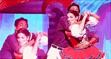 a group of people are dancing on a stage and one of them is in a red dress