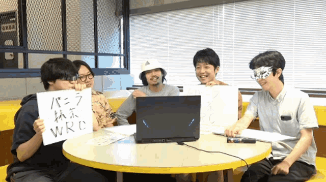 a group of people sitting around a table holding up signs that say wrc