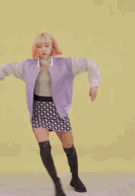 a woman wearing a purple jacket and black and white checkered skirt is dancing