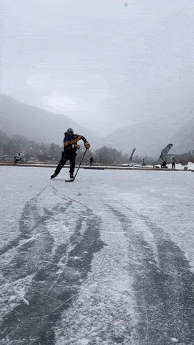 a man is playing ice hockey on a frozen lake with mountains in the background