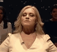 a woman in a white shirt is sitting in front of a group of people .