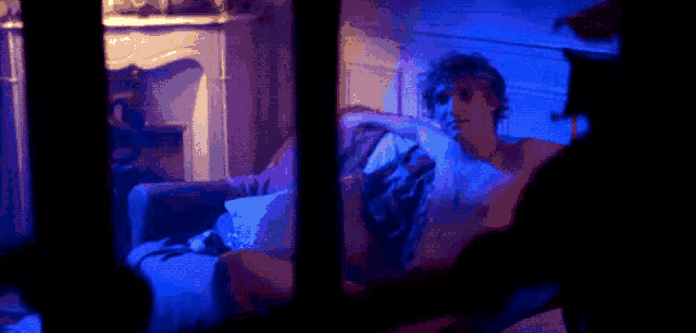 a man is laying on a couch with his arms outstretched in a dark room