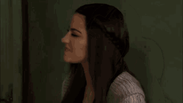 a woman with long hair and a gray sweater looks down