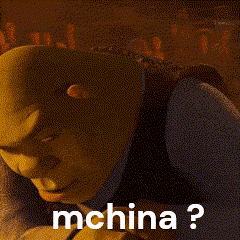 shrek is wearing a suit and tie and has the words `` mchina ? '' written on his face .