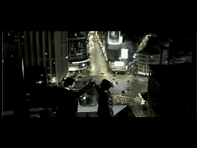 a group of people standing on top of a building overlooking a city at night