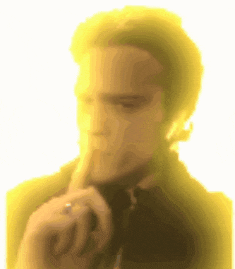a man with a ring on his finger is holding his finger to his mouth .