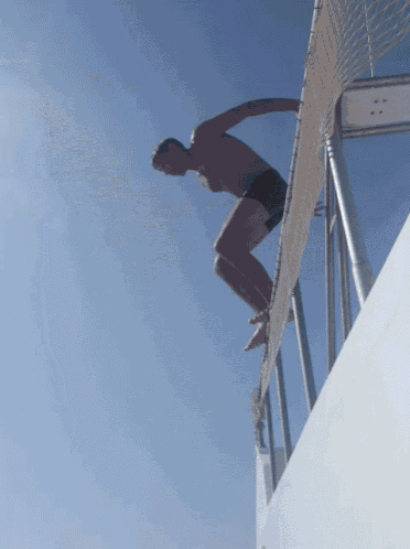 a man is jumping over a fence into a body of water