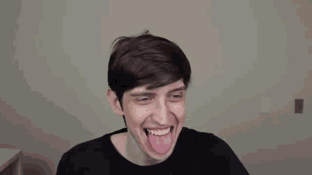 a young man is making a funny face while sticking his tongue out .