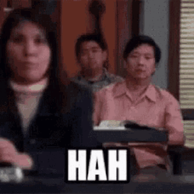 a woman is sitting in front of a group of people in a classroom with a sign that says nah .