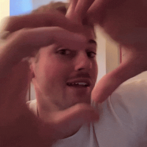 a close up of a man making a heart with his hands