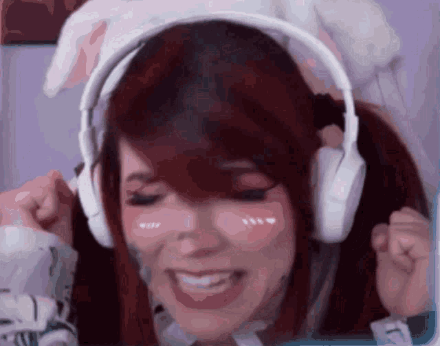 a girl with red hair is wearing headphones and smiling .