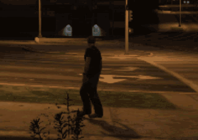 a man walks down a street at night in front of a sign that says ' a & r ' on it