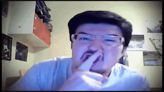a man with glasses and a mustache is covering his nose with his hand