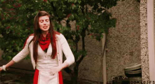 a woman in a red and white dress is dancing in front of a tree ..