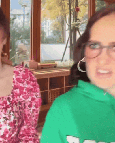 a woman wearing glasses and a green sweatshirt with a white s on it