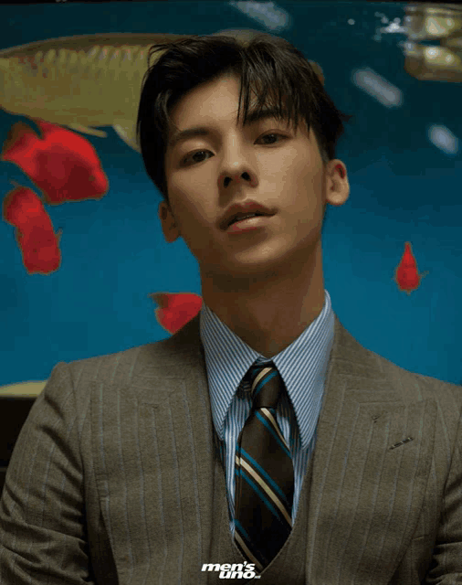 a man in a suit and tie is standing in front of a fish tank