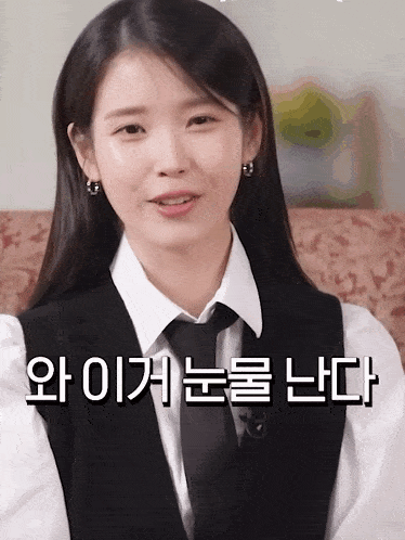 a woman wearing a vest and tie with korean writing on the bottom right