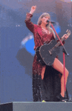 a woman is singing into a microphone while holding a guitar ..