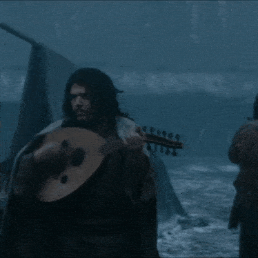 a man is playing a guitar while another man plays a drum