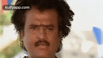 a close up of a man 's face with a mustache and earrings .
