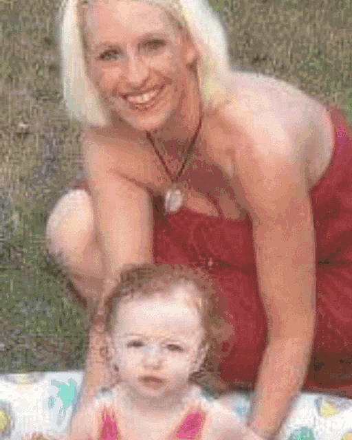 a woman in a red dress kneeling next to a baby