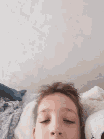 a child is laying on a bed with his eyes closed .
