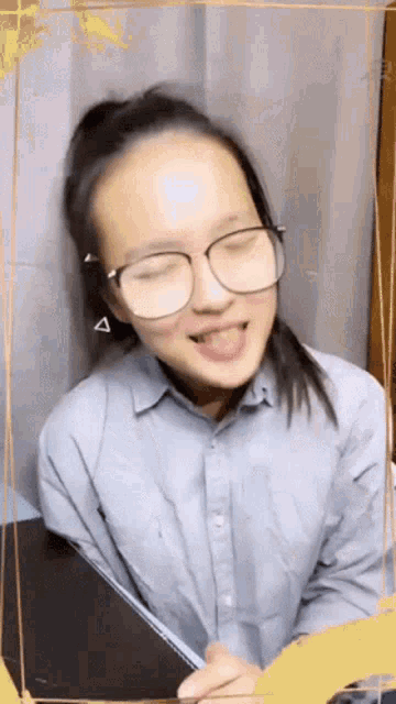 a young girl wearing glasses and a blue shirt is making a funny face